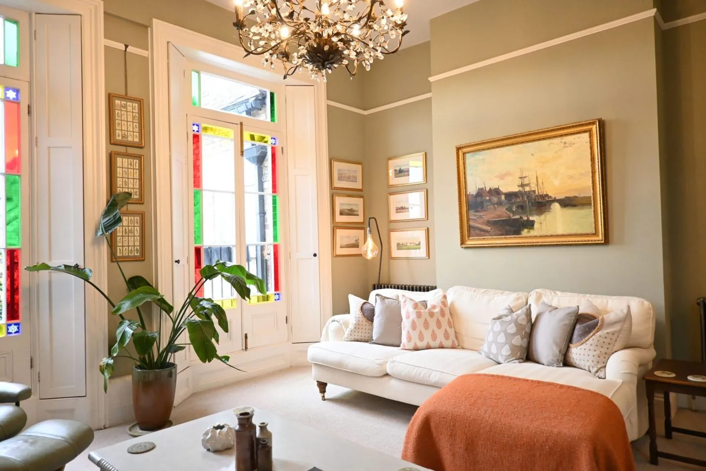 Your light-filled living space is framed by striking floor-to-ceiling windows, where soft pastel tones and comfortable seating create the perfect place to unwind after a day exploring Sandwich or the nearby coast.