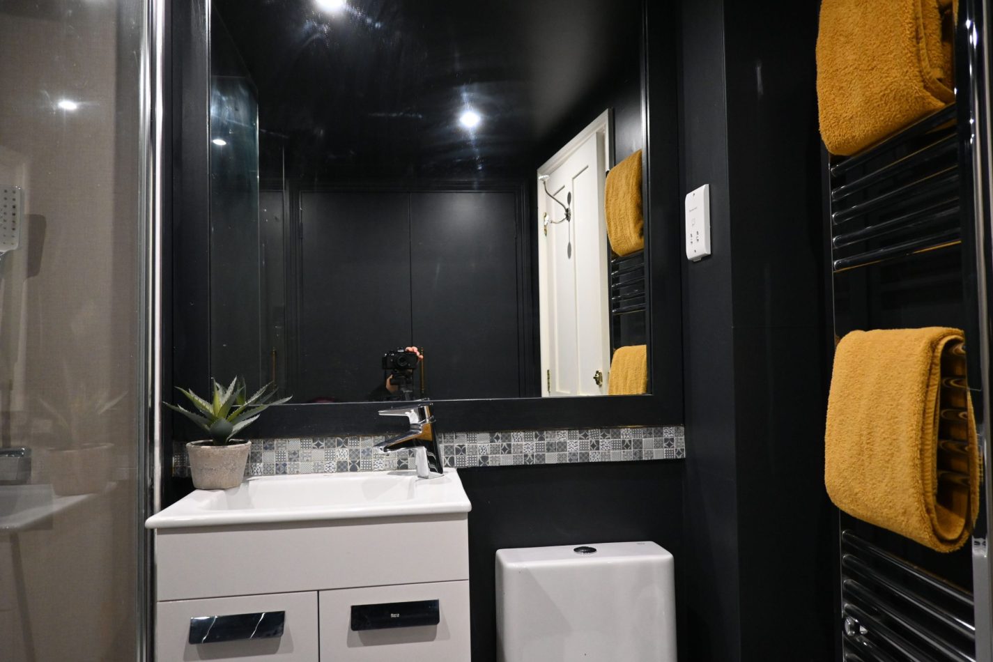 Your stylish family shower room pairs sleek dark greys with warm yellow accents, creating a modern, inviting space—perfect for refreshing after days exploring Sandwich, the coast or nearby golf courses.