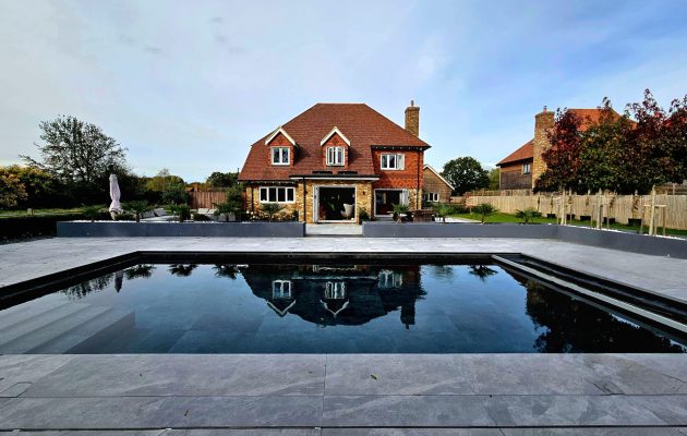 Take in the rear view of the house with the outdoor heated pool set in front, surrounded by generous grounds. A stunning backdrop for summer stays, group getaways and luxury holiday living in Kent.