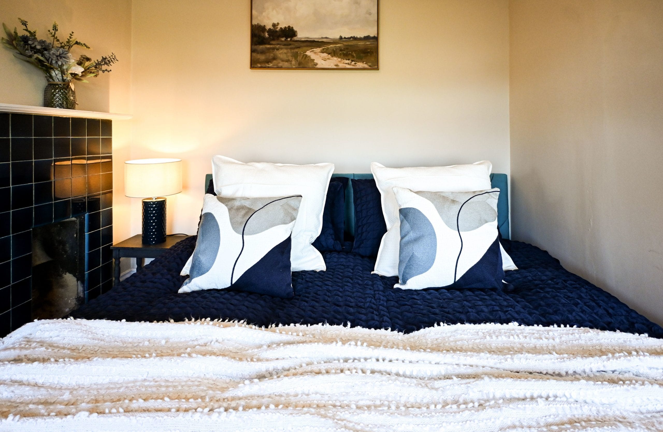 Beautifully dressed with crisp white bedding, deep blue accents and plump cushions, this inviting bed promises a comfortable retreat after a day of seaside adventures.
