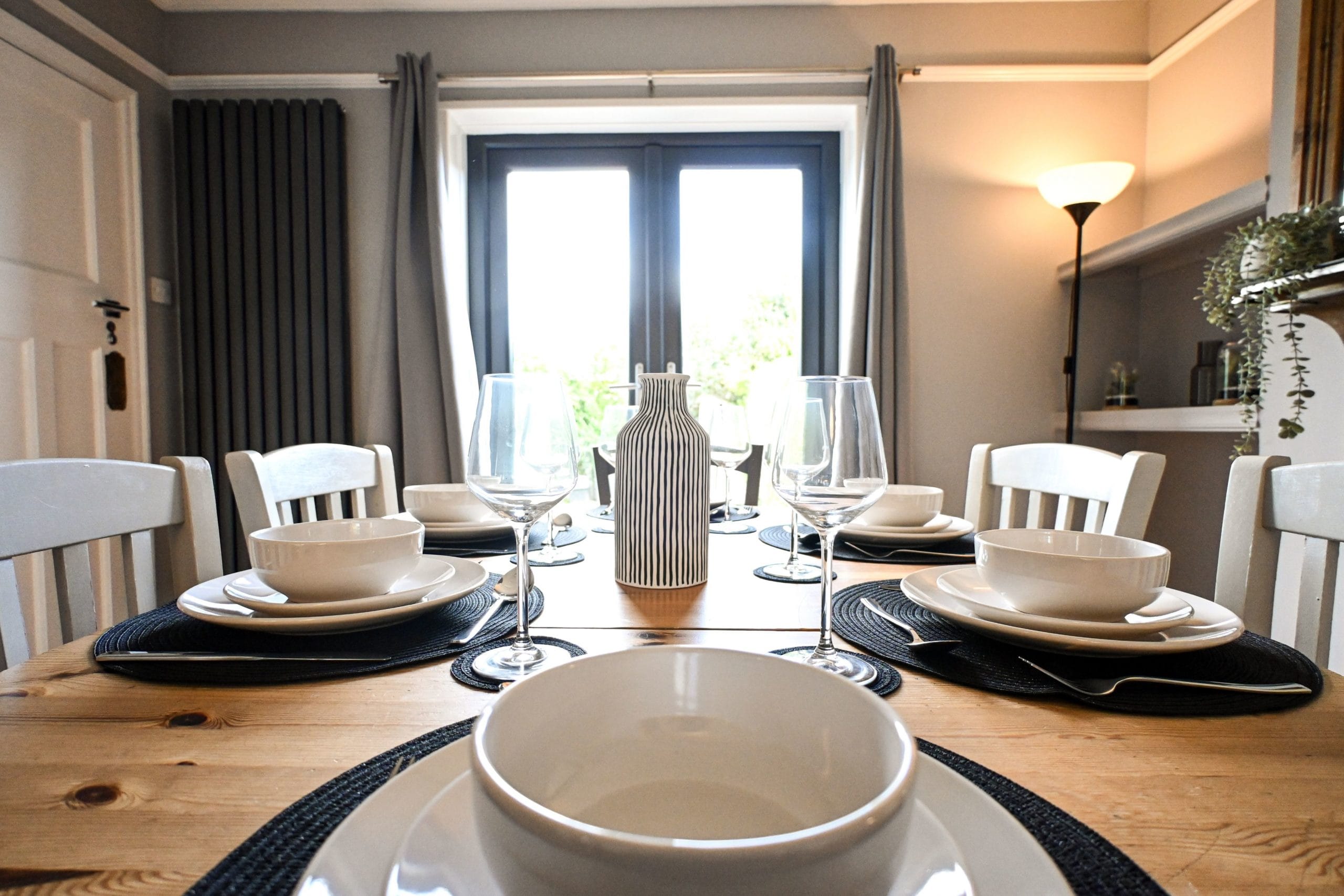Gather around the wooden dining table for leisurely breakfasts, delicious dinners and a glass of wine together, with French doors opening towards the garden beyond.