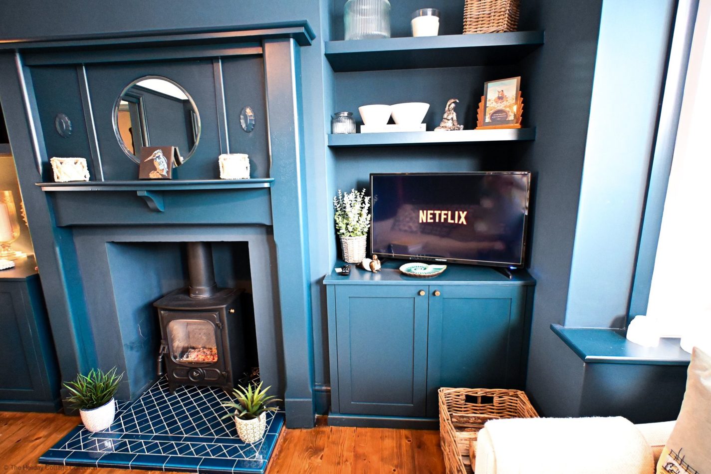 Rich blue cabinetry, carefully chosen decorative touches and a welcoming log burner give the lounge its distinctive character. The smart TV finishes off a place to relax whatever the season